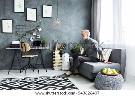 Hipster man sitting on a sofa in flat apartment