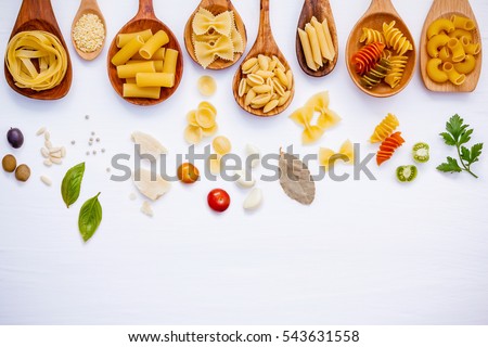 Italian food concept .Various kind of pasta with ingredients sweet basil ,tomato ,garlic ,parsley ,bay leaves ,pepper ,pine nut  and parmesan cheese on white wooden background flat lay and copy space. Royalty-Free Stock Photo #543631558