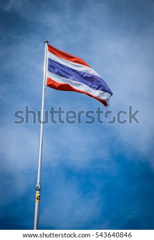 A Thai national flag place on the top of the mountain and surround with blue sky.