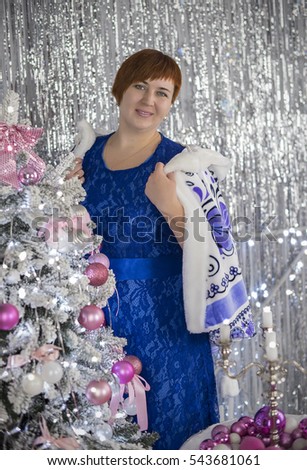 beautiful woman in a blue evening dress posing near the Christmas tree