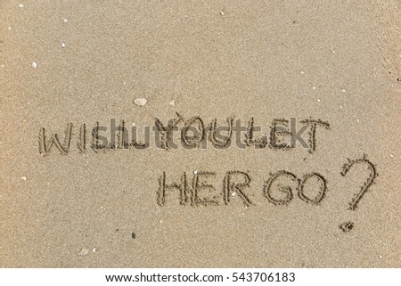 Handwriting words "WILL YOU LET HER GO?" on sand of beach