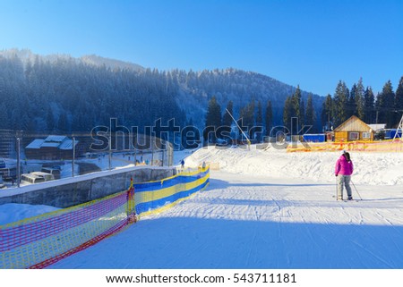 A place for downhill skiing in a mountain valley against a background of white snow, high mountains and a blue sky. Ski resort Bukovel in Ukraine. Skiing and rest in the mountains in winter.
