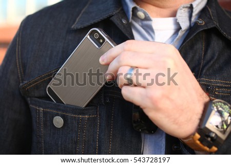 businessman pulling out a mobile phone or may be putting mobile in pocket Royalty-Free Stock Photo #543728197