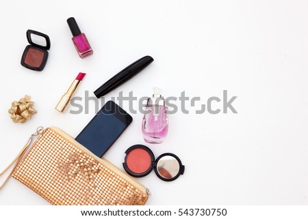 Feminine fashion background. Content of ladies handbag. Red lipstick, brush mascara, eyeshadow palette and nail polish. Flat lay beauty accessories for makeup and open yellow clutch. Top view photo