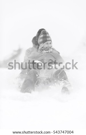 Cheerful young couple sledding in snow