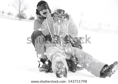 Excited young couple sledding in snow