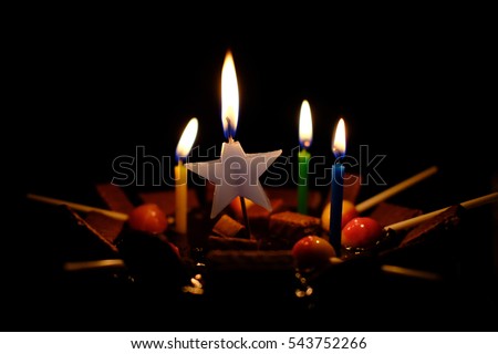 a light candle in darkness of birthday chocolate cake