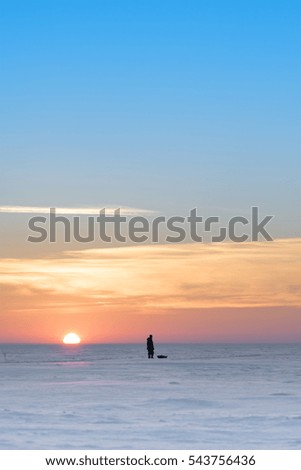 Siberia, Novosibirsk region, Ob reservoir in winter, fishermen returning from ice fishing on sunset background