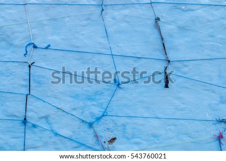 Abstract string crossing and knots over a blue wall.