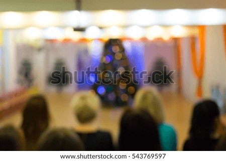 Blurred background Christmas tree and seated people. New year party