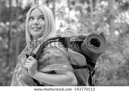 Side view smiling female backpacker in raincoat looking away at forest