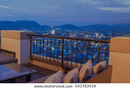 Restaurant dining table and view of business building on terrace at twilight overlooking the city at night / soft focus picture