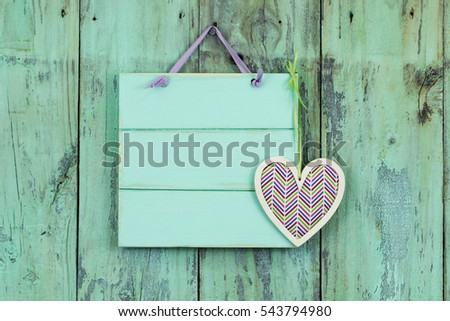 Blank mint green sign with country geometric design heart hanging on antique rustic wood door; Valentine's Day and love concept with wooden painted copy space