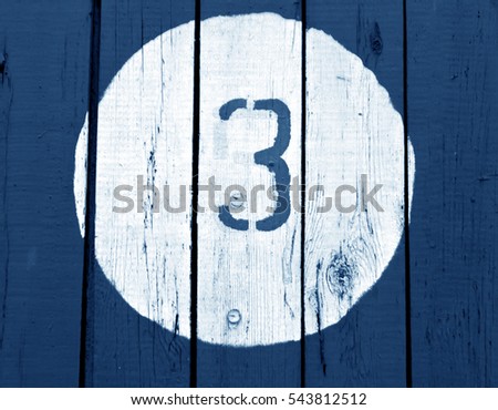 Number three on wooden blue toned wall. Numbers and figures.