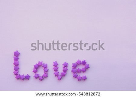 Inscription "Love" made from small paper colored stars Origami. Text "Love" written by small elements of paper. Valentine's day theme. Flat Lay. Close-up. 
