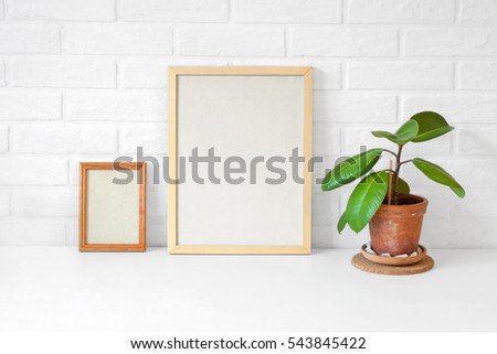 Two empty wooden picture frame with copy space on table with a painted white scandinavian loft nordic brick wall background. Craft paper texture. Green flower ficus. Home crafts. Mock up. Ecology