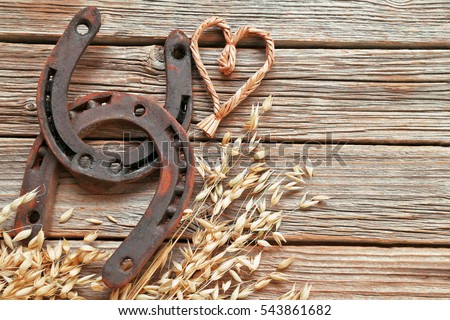 Horseshoes with oat, straw heart  on wooden background 