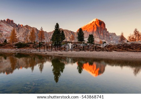 Amazing sunset scenery on Limides Lake (Lago di Limides) and Tofana di Rozes mountain on background with reflections in water. Colorful autumn evening near Falzarego Pass, Dolomite Alps, Italy.