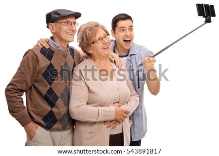 Cheerful seniors and a young man taking a selfie with a stick isolated on white background