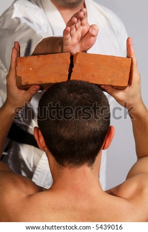 karate man breaking  brick on the head of a sportsman