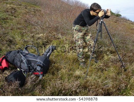 handsome young photographer taking landscape photos outdoors