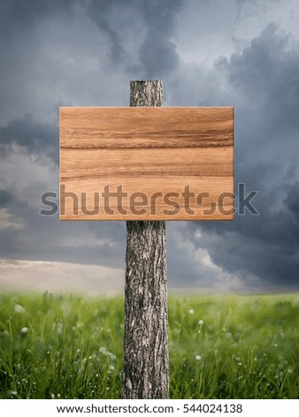 Wooden sign board background in grass field area and storm cloud background.