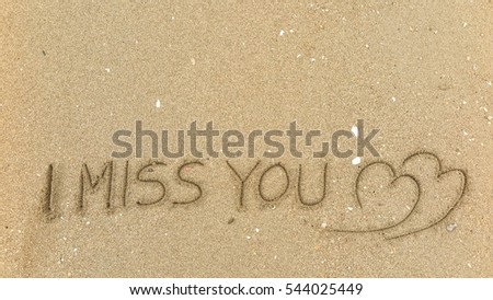 Handwriting words "I MISS YOU" on sand of beach