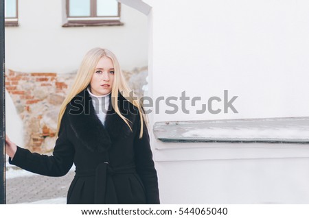 Portrait of a beautiful young blonde woman in autumn time near metal gate