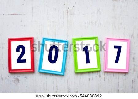2017 number on color photo frame over white rustic wooden background, Happy New Year concept