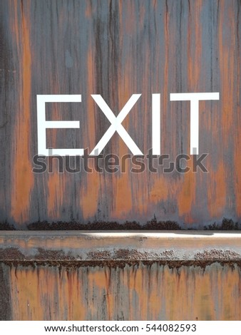 The word EXIT as signage on the rust steel wall