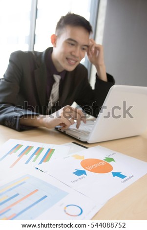 Strategic documents are on the table while business man is slightly blurred in background.