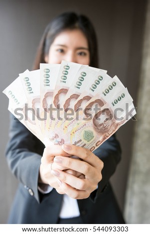 Asian women is showing Thai bank note.