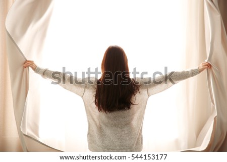 Girl opening curtains Royalty-Free Stock Photo #544153177
