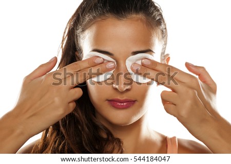 beautiful young woman holding a cotton pads on her eyes