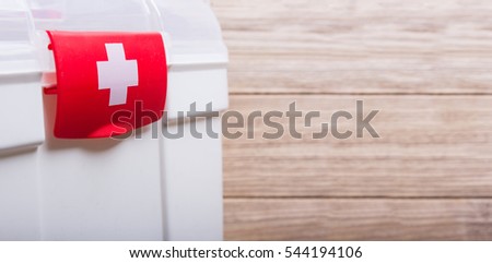 White Case with red clasp and a white cross. Wooden table background
