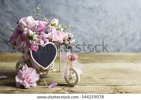 Pink carnation in bicycle with blank wood heart on old wood