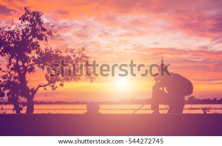 Silhouette of a young man using a camera sunset.
