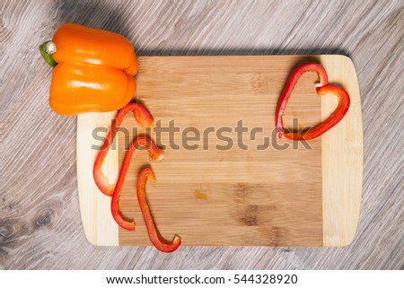 Red and orange paprika on cutting board. Red pepper strips whit wood background.