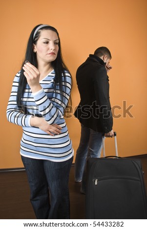Couple divorce,woman standing with wedding ring in hand and cry away and man leave the house with baggage