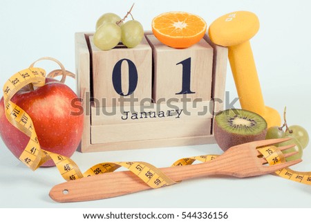 Vintage photo, January 1 on cube calendar, fresh fruits, dumbbells and tape measure, new years resolutions of healthy lifestyle