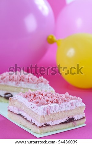 Slices of nice pink cake with some balloons on the background