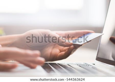 Hands holding credit card, typing on the keyboard of laptop, onine shopping detail close up