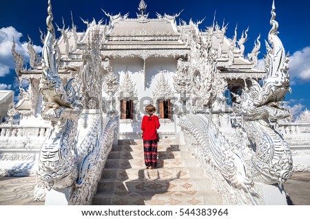 Woman in red shirt in front of Wat Rong Khun The White Temple in Chiang Rai, Thailand Royalty-Free Stock Photo #544383964