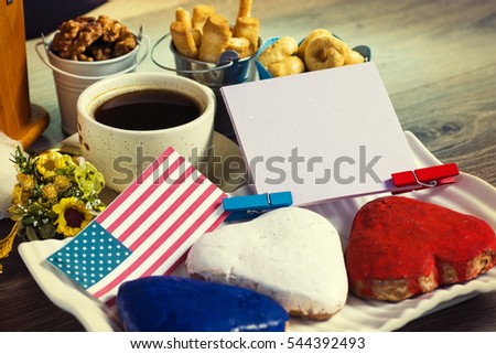Patriotic party Concept -  Heart shaped cookies color red, blue, white. Cup of coffee (tea), USA flag, decoration on old wooden table. toned filter image. space for text