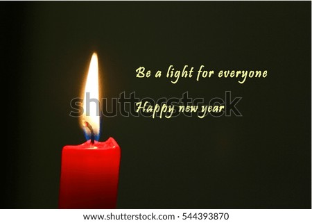 Red candle illuminating dark background with english text and happy new year