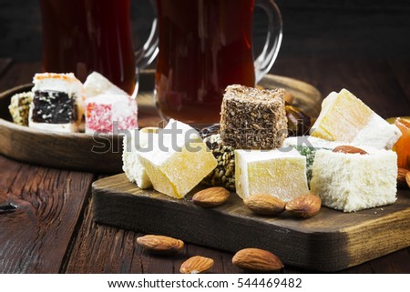 Black tea, oriental sweets, dates and nuts on a dark wooden background. Toning
