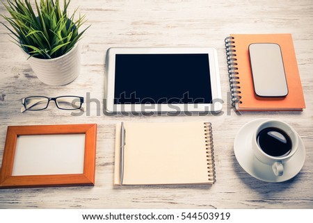 Still life photo of tablet notepad coffee glasses on wooden table