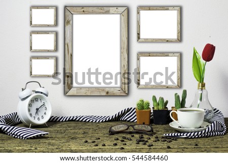 Wooden workplace desktop with table clock, coffee cup, plants,flower, Frame on old wooden table.