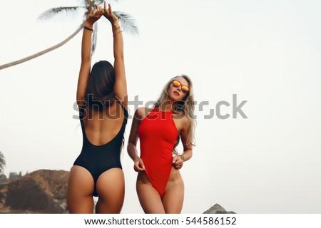 summer Portrait of two glamour friends on the beach looking at camera laughing.girls in similar bikini