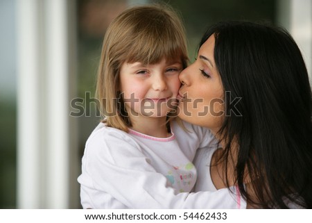 Portrait of a young woman carrying and kissing a little girl